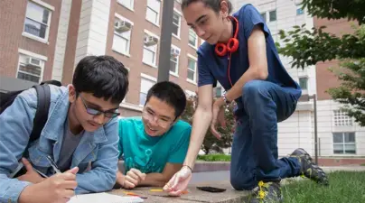 Three students working on a project outside on campus.
