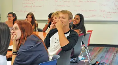 Students smiling and listening in a classroom.