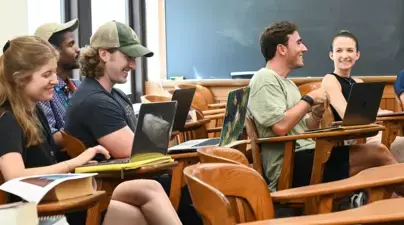 Students laughing in a classroom at their desks.