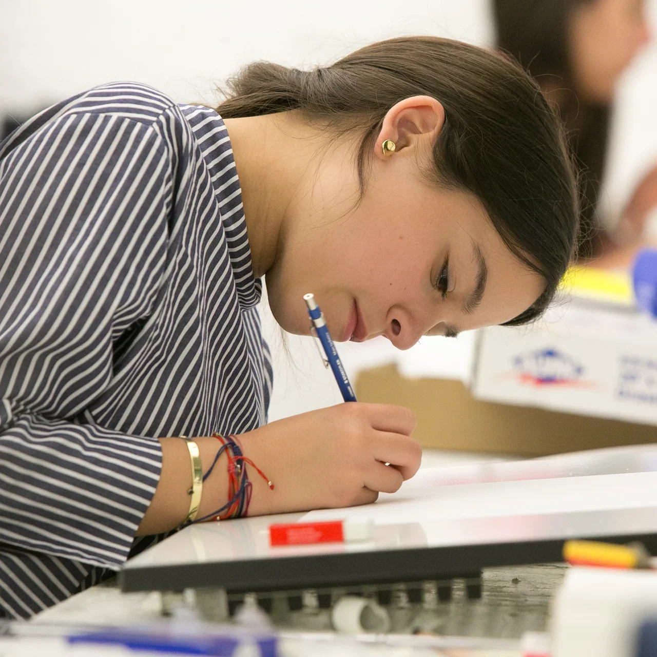 A student writes at a desk.