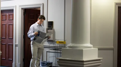 The Owl’s Hoot Editor in Chief Brady Ehrhart reads through an edition of the paper outside the publication newsroom in spring 2026. 